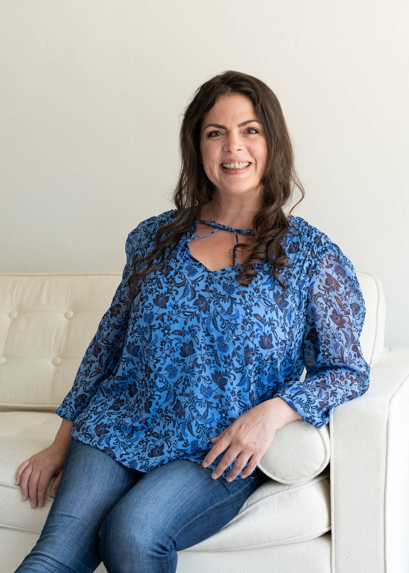 Gethen Christine Morris seated on a white sofa in a blue floral blouse